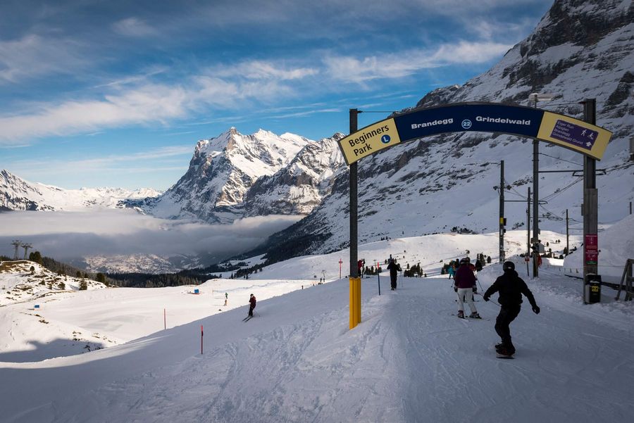 Snowboarder und Skifahrer auf der weissen Piste mit Bergblick