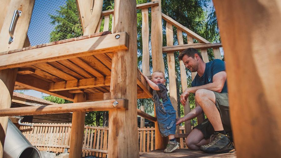 Ein Vater spielt mit seinem Kind auf dem Spielplatz im Freilichtmuseum Ballenberg