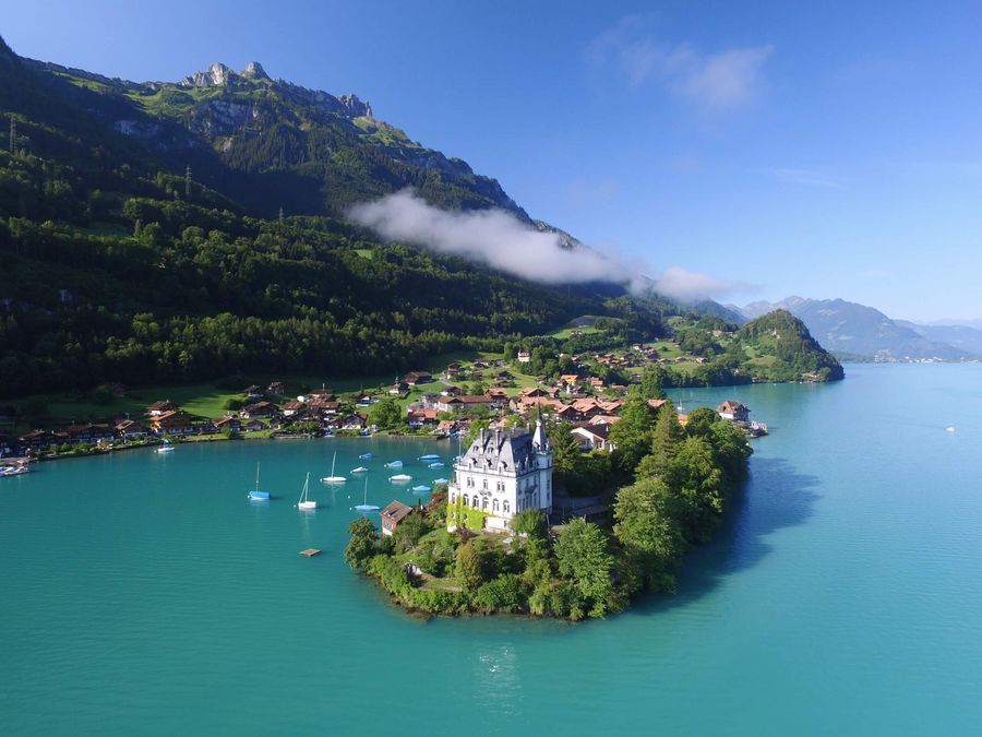 Eine feine Nebelschwade hängt über dem malerischen Dorf Iseltwald. In der Bucht treiben mehrere Boote.