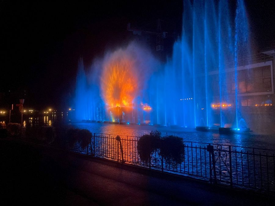 Wasserspiel mit blauen Fontänen und orangem Kreis in der Mitte am Thuner Wasserzauber auf der Aare neben dem Hotel Freienhof in Thun