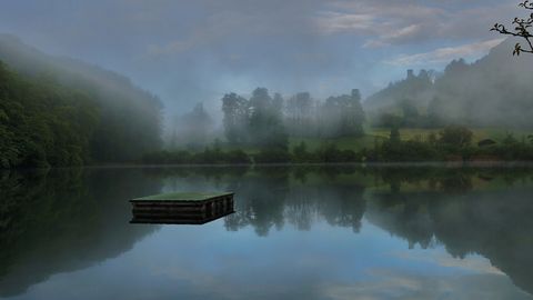 Naturstrandbad Burgseeli mit spiegelglattem Wasser in dem sich die Bäume spiegeln