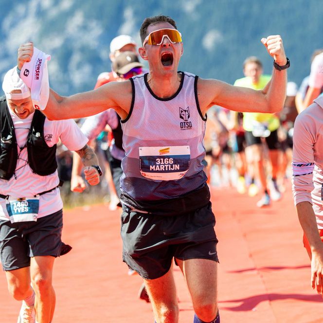 Der Läufer Tobias Giesser jubelt über seinen Einlauf im Ziel des Jungfrau-Marathons und seinen 26. Rang vor zwei Zieldamen in einer traditionellen Tracht